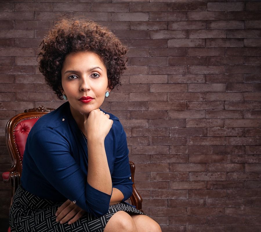 Retrato profissional de executiva sentada, com fundo de tijolo, feito em estúdio no Alto da Lapa, São Paulo.
